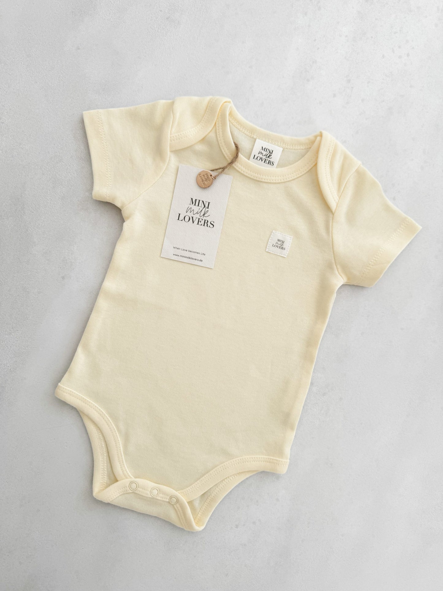 Short-sleeved bodysuit in the trendy color butter, made from organic cotton