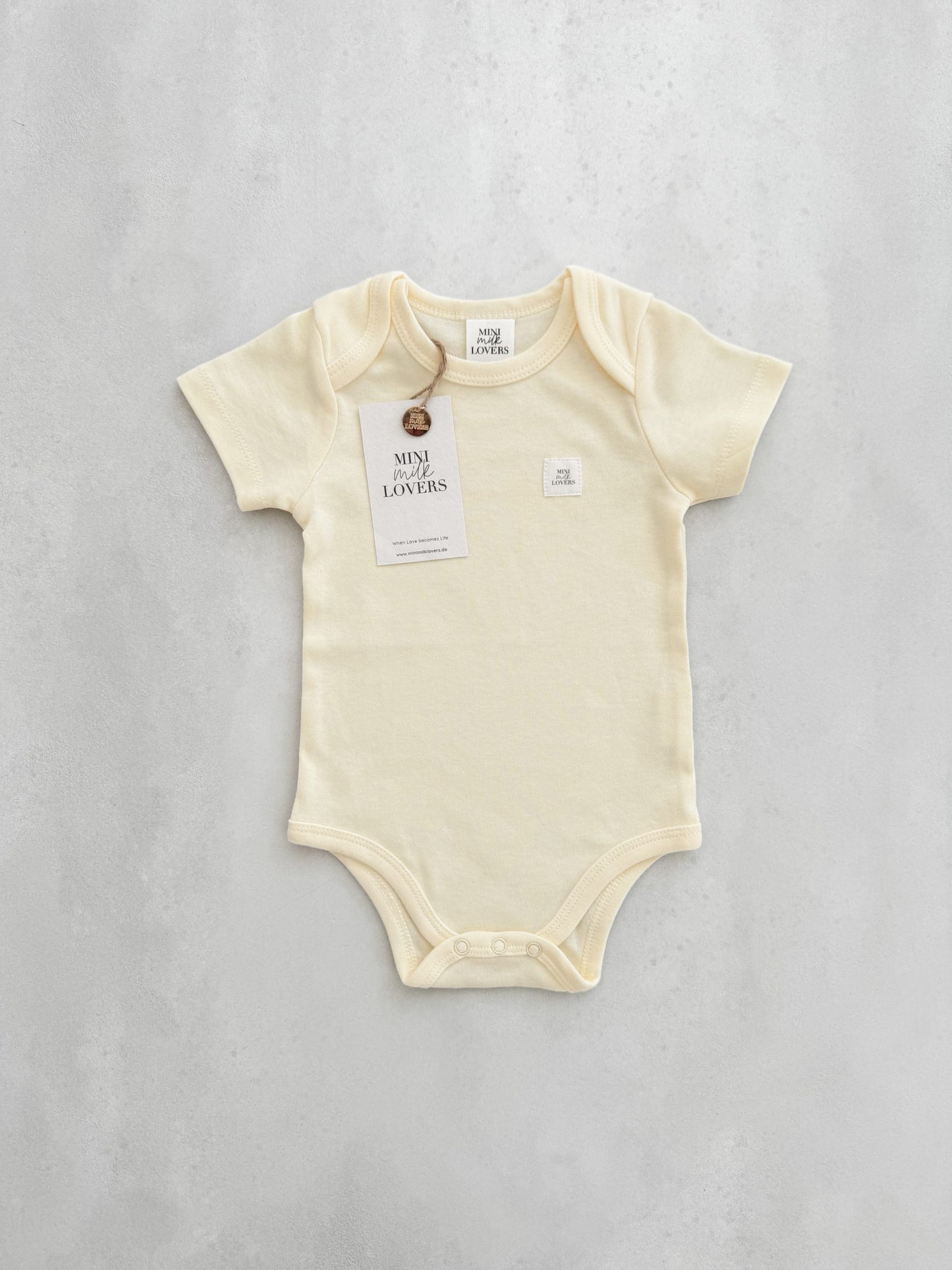 Short-sleeved bodysuit in the trendy color butter, made from organic cotton